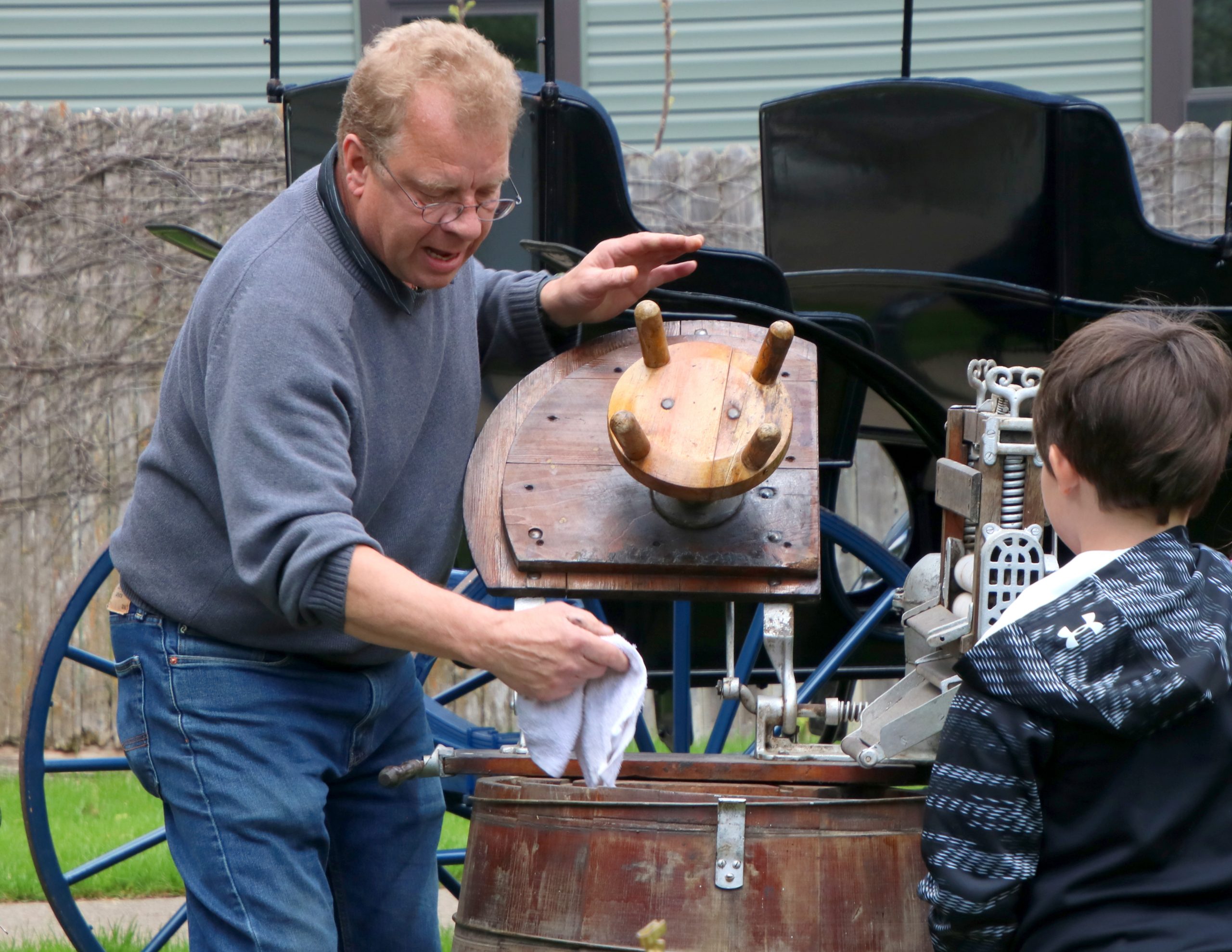 A man shows a student an old-fashioned washing machine. 